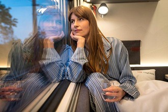Woman in the comfort plus sleeping car looks dreamily out of the window