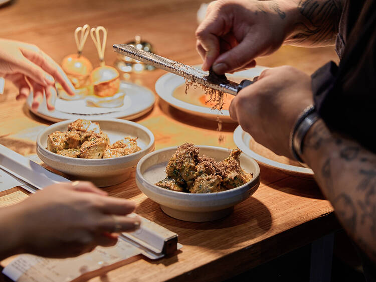 A chef grating truffle atop a dish.