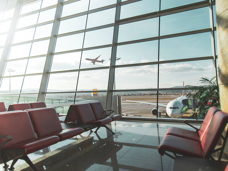 Airport departure gate with planes taking off in background