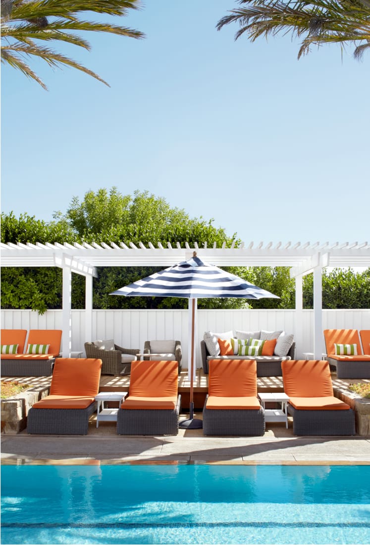 A refreshing pool surrounded by comfortable lounge chairs and shaded umbrellas.