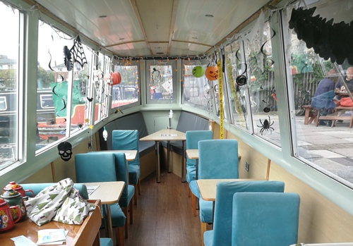 Boat cabin with tables and chairs each side of corridor,