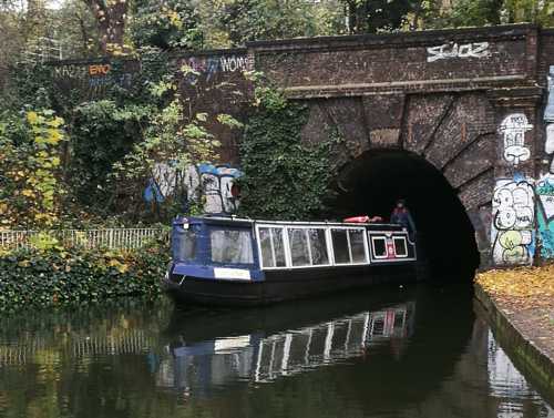 Passenger boat with big windows emerges from tunnel portal