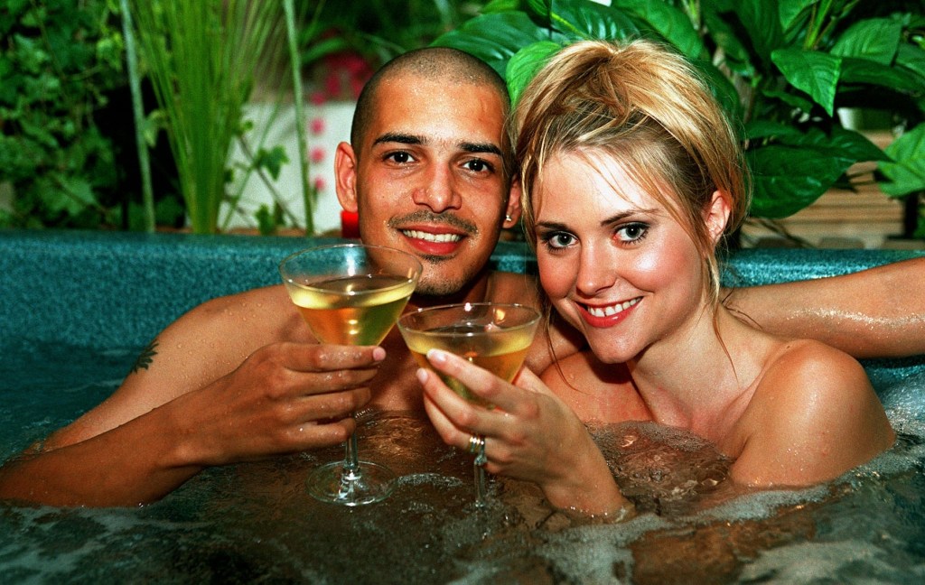Ian Walmsley (Nathan Constance) and Donna Walmsley (Katharine Monghan) in a hot tub with drinks.